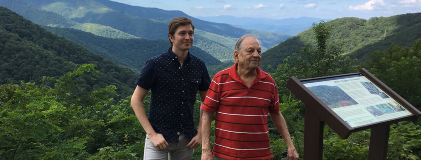 Phillip Gregory, left, stands with his uncle, Bruce Gregory, by a sign off the Blue Ridge Parkway, the design and construction of which Bruce contributed to in the 1960s.